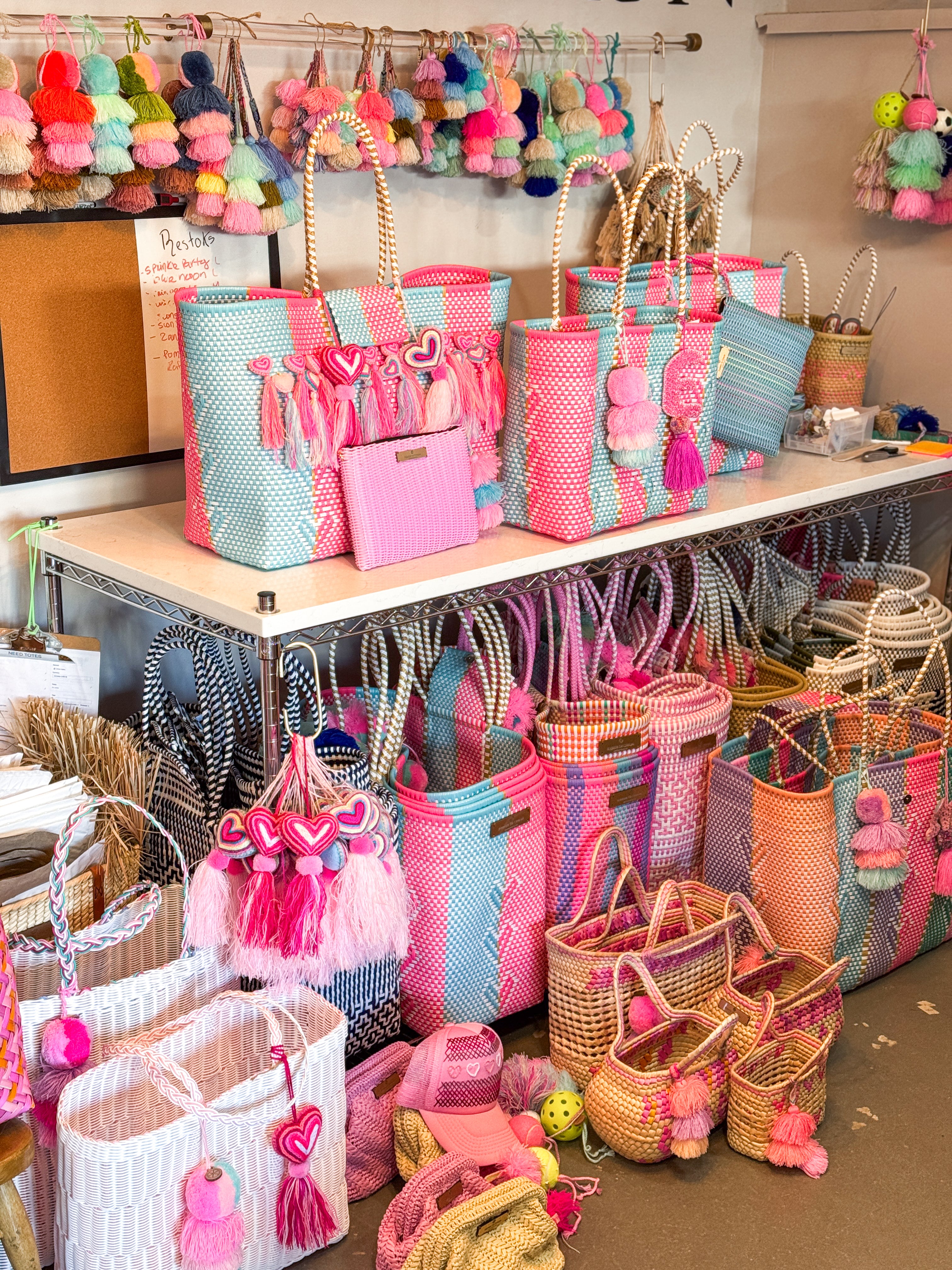 Display of colorful handbags and accessories on a table with various designs and colors.